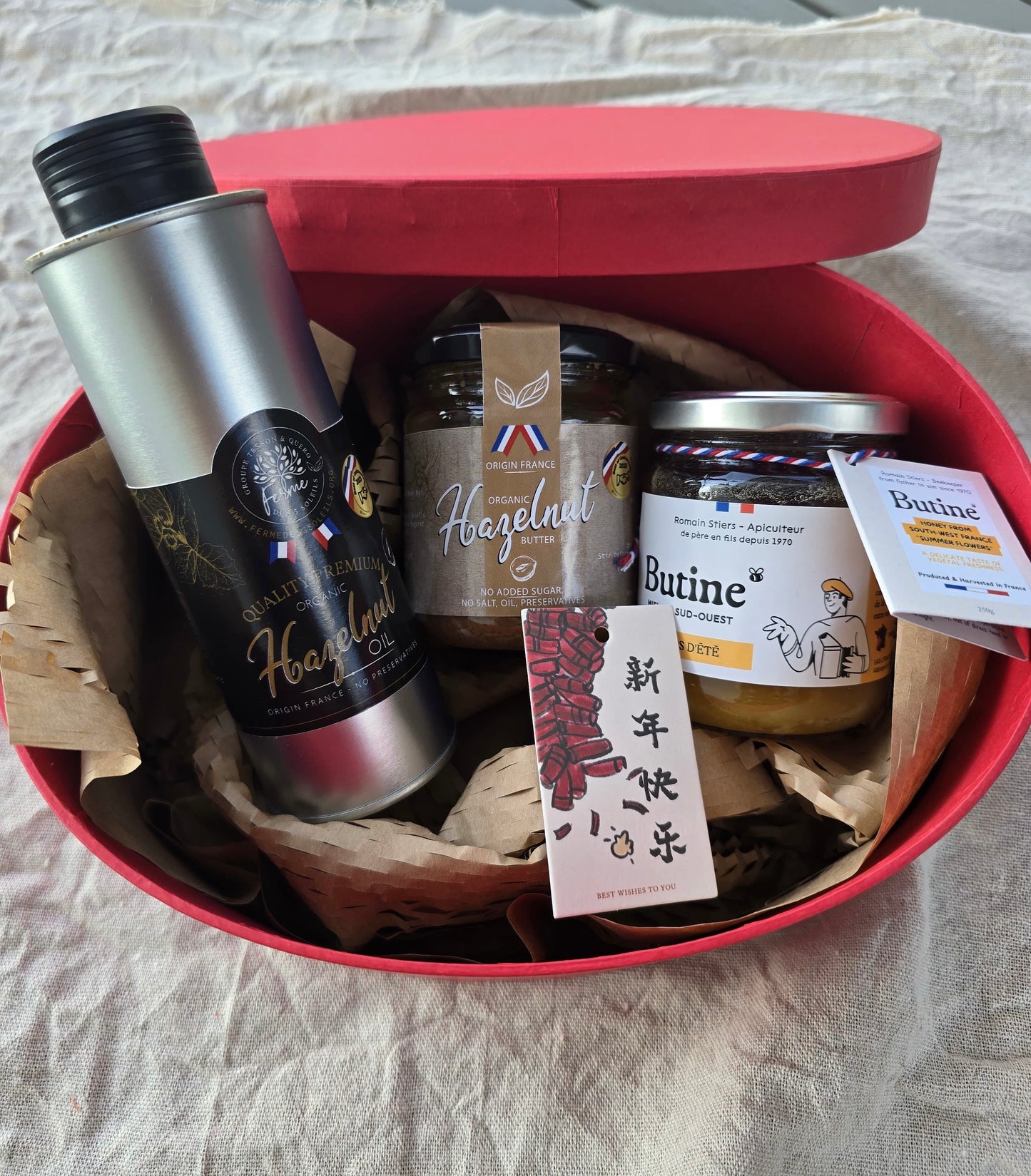 Gift basket with a thermos, jars, and a card on a textured surface