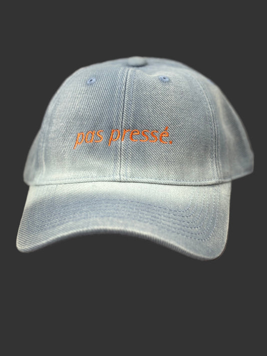 Light blue cap with 'pas presé' text on a brown background