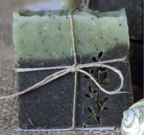 Two bars of soap, one green and one brown, tied together with twine on a textured surface.